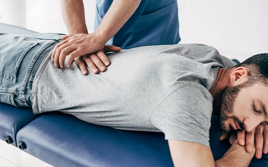 Man Lying On Blue Table Receiving Adjustment